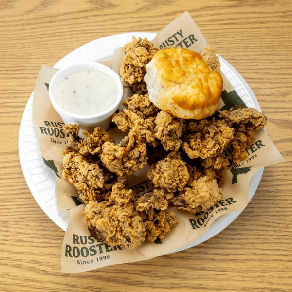 Crispy fried chicken livers with a biscuit and gravy on a Rusty Rooster branded paper liner.